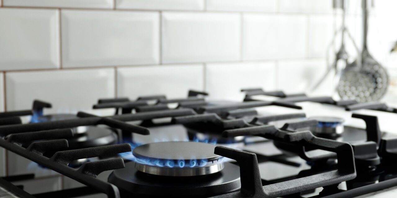 Closeup shot of blue fire from domestic kitchen stove top. Gas cooker with burning flames of propane gas. Industrial resources and economy concept.